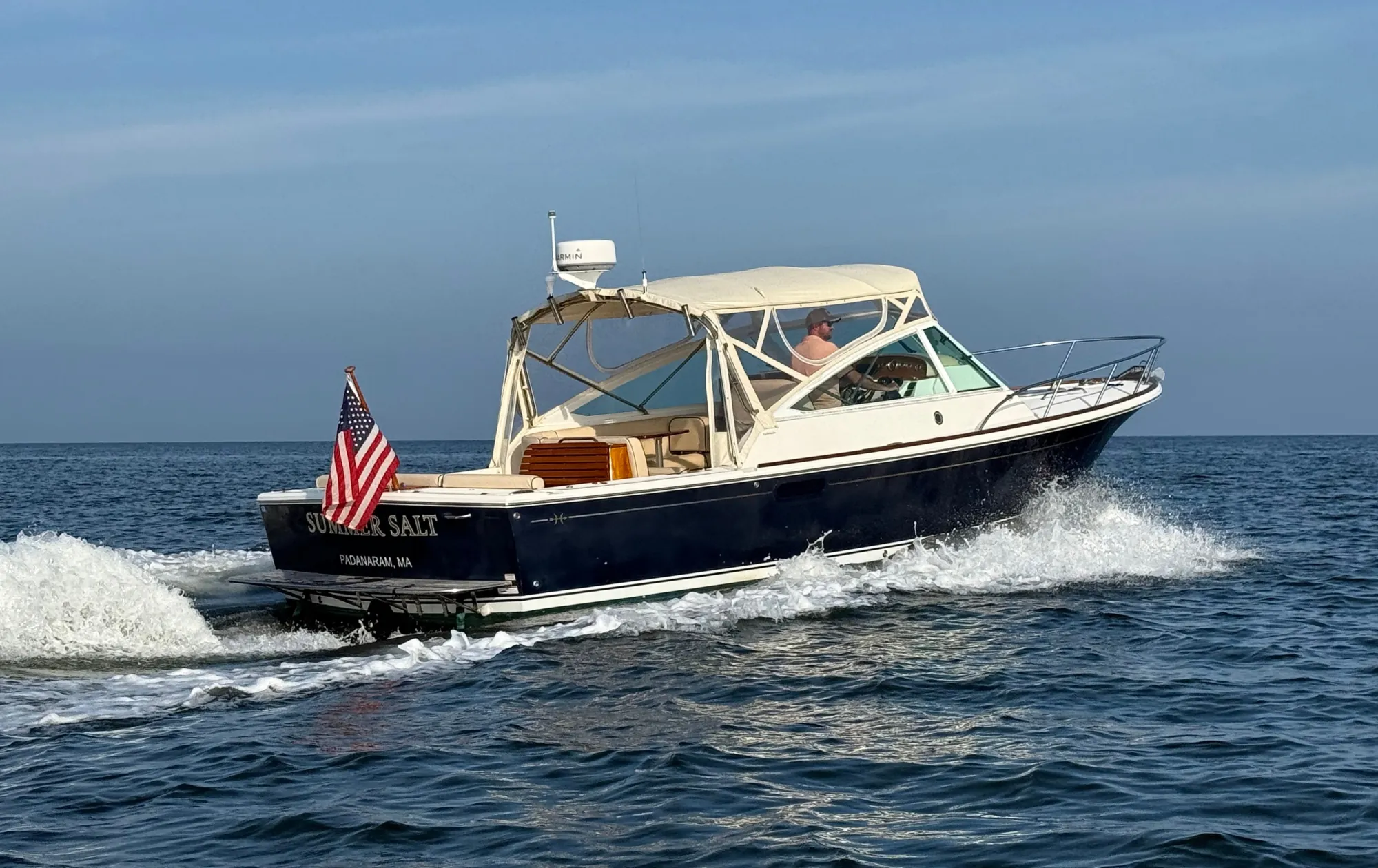 Summer Salt, a navy-hulled express cruiser, under way at speed